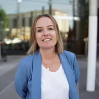 Professional headshot of a smiling woman in a blue blazer.